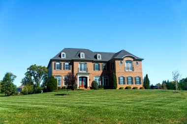 Luxurious large single family brick house with large green lawn. Landscape on a summer sunny day.