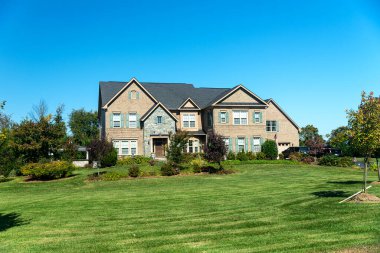 Two-story brick and stone house with a garage and a green lawn
