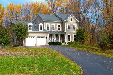 Beautiful autumn exterior of the house. Yard with green grass and path leading to the garage.