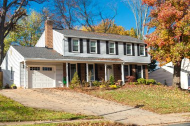 Beautiful autumn exterior of the house. Yard with green grass and path leading to the garage.