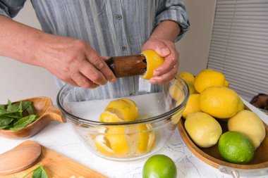 Mutfaktaki kadın limonata yapmak için limon suyu sıkıyor..