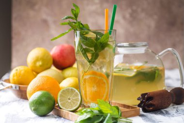Refreshing lemonade with lemon and mint in a glass and decanter. Mortar and pestle and fresh mint. space for text.