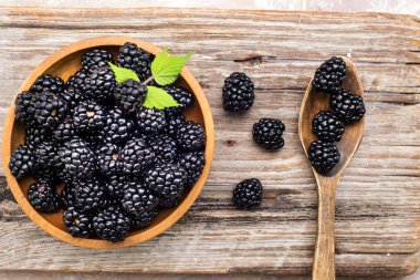 fresh blackberries in a wooden plate and spoon. View from above. Space for text.