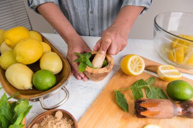 Hands crush mint with a pestle in a mortar. Making majitos or homemade lemonade.