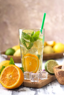 glas with lemonade or mojito cocktail with lemon and mint, cold refreshing drink or beverage with ice. The ingredients for the drink are lemons, mint, ice and lime.