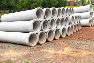 İnşaat alanına yığılmış yeni beton borular. Kanalizasyon sisteminin üretimine hazırlık.