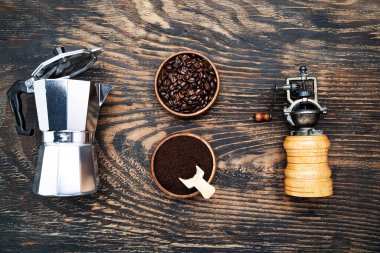 Coffee beans, ground coffee and a geyser coffee maker on a dark wooden table. View from above.