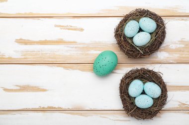 Branch nests and Easter eggs on a white wooden table. View from above. Space for text.