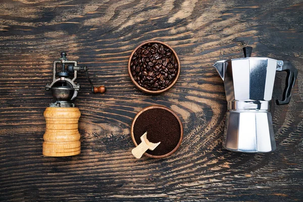 Coffee beans, ground coffee and a geyser coffee maker on a dark wooden table. View from above.