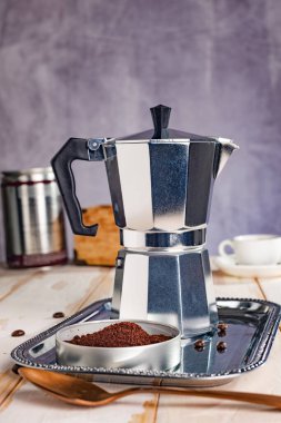 Gayzer kahve makinesi beyaz bir mutfak masasında duruyor. Kokulu bir içecek için her şey hazır..