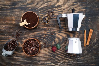 Coffee beans, ground coffee and a geyser coffee maker on a dark wooden table. View from above.