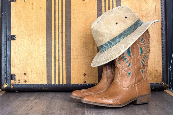 Cowboy boots and hat with vintage suitcase. Adventure and travel concept. Space for text.