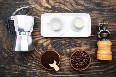 classic manual aluminum metal geyser coffee maker and porcelain tableware for coffee drinking on a dark wood background. View from above.