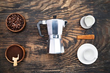 Cup of coffee, geyser coffee maker, milk and beans coffee on  bleck wooden table. top view.