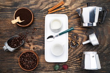 Cup of coffee, geyser coffee maker, milk and beans coffee on, dark wooden table. top view.