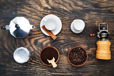 classic manual aluminum geyser coffee maker, and porcelain tableware for coffee drinking on a dark wood background. View from above.