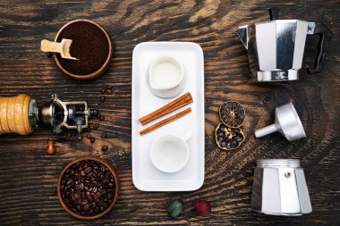 classic manual aluminum geyser coffee maker, and porcelain tableware for coffee drinking on a dark wood background. View from above.