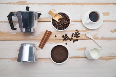 Cup of coffee, geyser coffee maker, milk and beans coffee on ,white wooden table. top view.