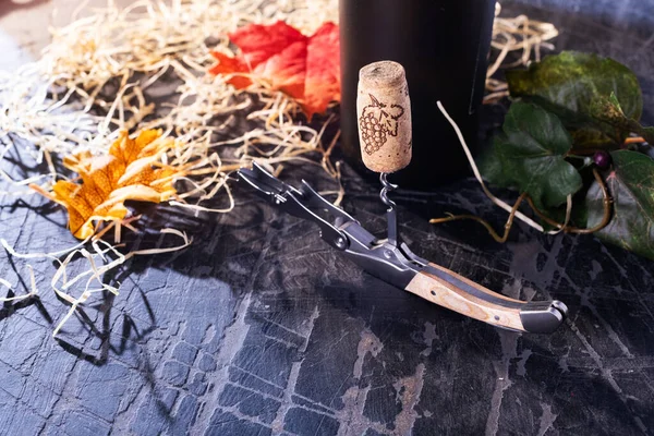 Corkscrew and cork with a bottle of old wine. Autumn and harvest concept.