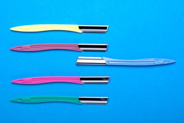 multi-colored women's razors with plastic handles on a blue background. Space for text.