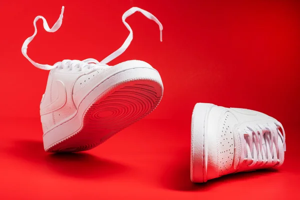 Para Adidasów White Nike Sfilmowanych Czerwonym Tle Zbliżenie — Zdjęcie stockowe