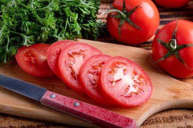Plastiklerle dilimlenmiş olgun domates ve kesme tahtasında bir bıçak. makro fotoğrafçılık.
