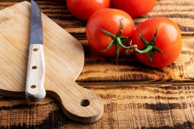 Taze, olgun bir domates ve kesme tahtasındaki bir bıçak. Metin için boşluk.