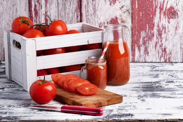 木製の箱と白いテーブルの上にトマトジュースのボトルで新鮮なトマトを熟す — ストック写真