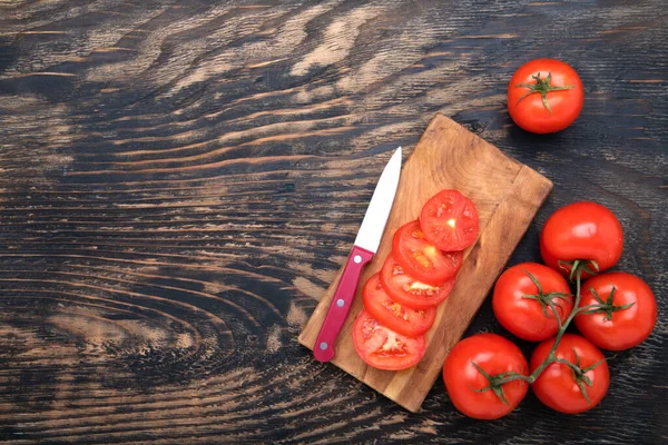 トマトスライスとまな板のナイフと暗い木の背景に新鮮なトマト 上からの眺め テキストのスペース — ストック写真