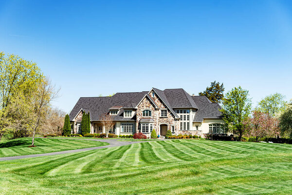 Large country house in the suburbs for one family. Brick house with a beautiful landscape and a large green lawn.