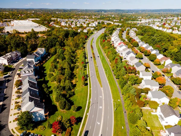 Panoramic aerial view of a cluster of houses with a road taken by a drone during the golden hour