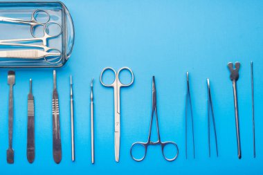 Mavi arka planda cerrahi aletler. Yukarıdan bak. Metin için boşluk.
