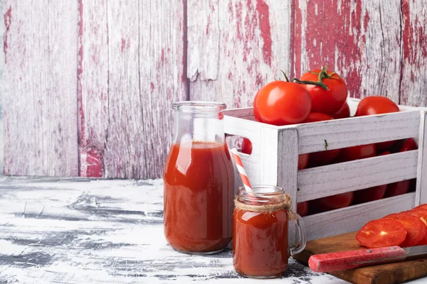 新鲜的西红柿放在白色桌子上的木箱里 番茄汁水壶和玻璃杯 — 图库照片