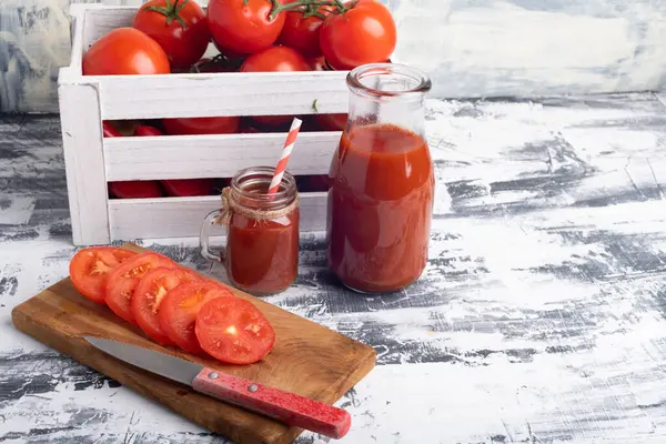 ガラス製品に新鮮なトマトジュース トマトジュースのグラスマグカップ 箱の中のトマトと木の板の上のトマトをスライスした テキストのスペース — ストック写真