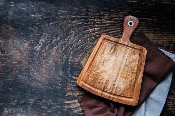 在黑暗的木制厨房桌子上的毛巾上切木板 从上面看案文的篇幅 — 图库照片