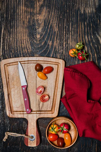 stock image fresh cherry tomatoes and knife on cutting board. Dark wooden table. View from above. copy space.