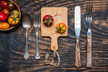 Tahtada iki olgun domates. Koyu ahşap masada çatal ve bıçak. Yukarıdan görünüm.