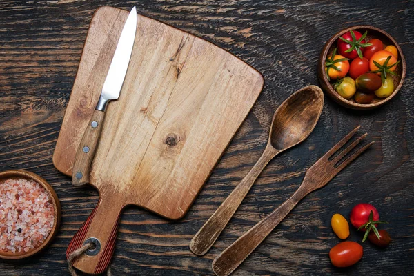 stock image cherry tomatoes, knife and cutting board on a dark wooden table. View from above. Space for text.