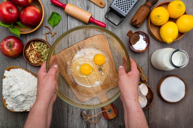 Kadın elleri elmalı turta pişirirken yumurta kırıyor. Yukarıdan görüntüle.