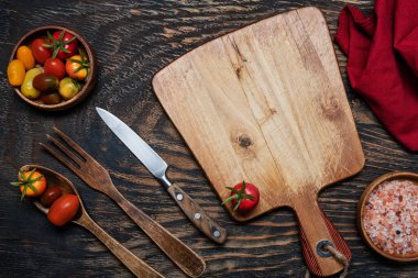 Çeri domatesleri, bıçak ve tahta kesme tahtası. Yukarıdan bak. Metin için boşluk.