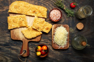 Fırında pişmiş Focaccia ya da pizza, domates ve peynirli karanlık bir masada. Yukarıdan görüntüle.