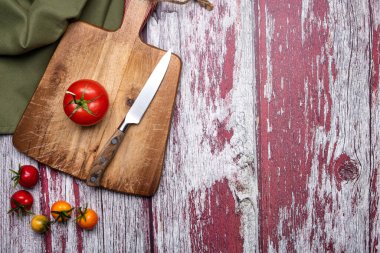 Kesme tahtasındaki domatesler eski boyalı tahtalarda bir bıçakla. Yukarıdan bak. Metin için yer.