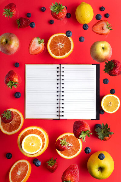 Summer fantasy. Fruits and berries on a red background. Notepad for text. Flying freshness. View from above. copyspace.