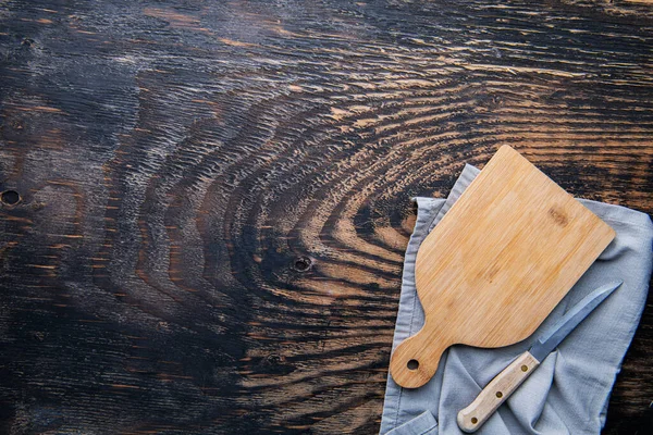 Pusta Drewniana Deska Cięcia Nóż Serwetka Ciemne Tło Stołu Widok — Zdjęcie stockowe
