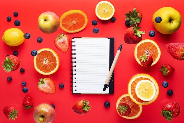 Refreshing food collection. background. apples oranges lemons, strawberries and blueberries. Summer vitamins levitate on a red background. Space for text. View from above.