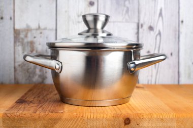 Ahşap bir masada paslanmaz çelik tencere. Yan görünüm.