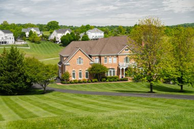 İngiliz tarzında büyük bir kır evi. Girişin önünde biçilmiş büyük bir çim var..