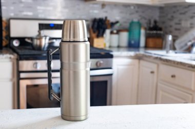 Çelik termos beyaz mutfak masasına yakın plan. Metin için boşluk.