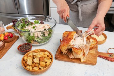 Kadın mutfakta sezar salatası hazırlıyor. Kızarmış tavuk parçaları salata kasesine eklenir. Bıçak ve eller yakın plan..