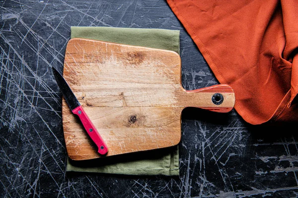 石材深色底座上有刀片和餐巾纸的木制切割板 — 图库照片